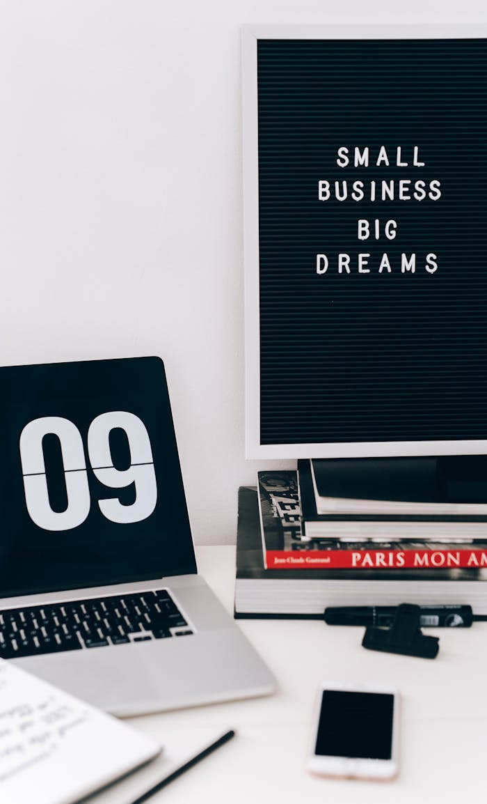 Modern workspace featuring a laptop, smartphone, and motivational quote board.